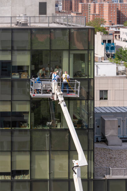 istock High-altitude work. Two teams of blue-collar workers working on the office building glass facade: one team from outside using the lifting platform, and another from inside. 1159530207