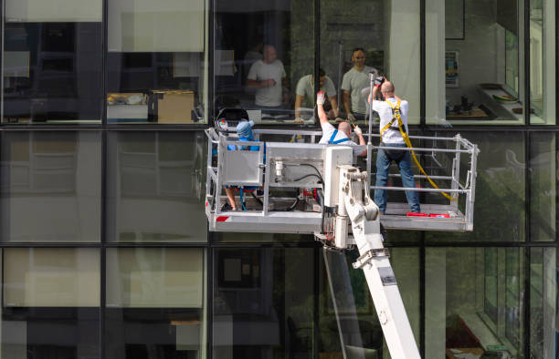 istock High-altitude work. Two teams of blue-collar workers working on the office building glass facade: one team from outside using the lifting platform, and another from inside. 1159530219