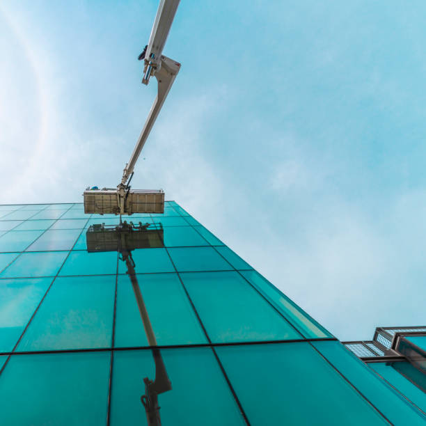 High-altitude work. Team of blue-collar workers working on the office building glass facade using the lifting platform.