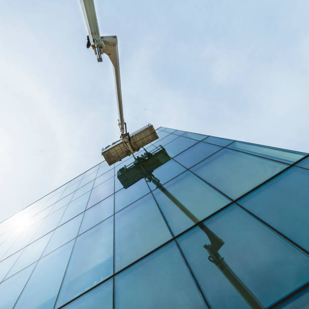 istock High-altitude work. Team of blue-collar workers working on the office building glass facade using the lifting platform. 1159530392