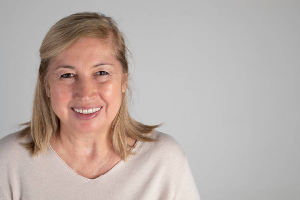 Smiling mature woman looking at camera, white background.