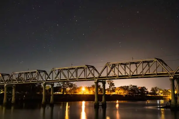 Railway bridge over the Burnett River in North Bundaberg lit up by the night sky