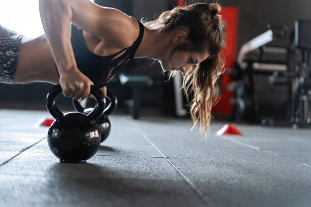sportive woman doing push-ups in the gym using kettlebells. - kettle bell activity aerobics athlete imagens e fotografias de stock