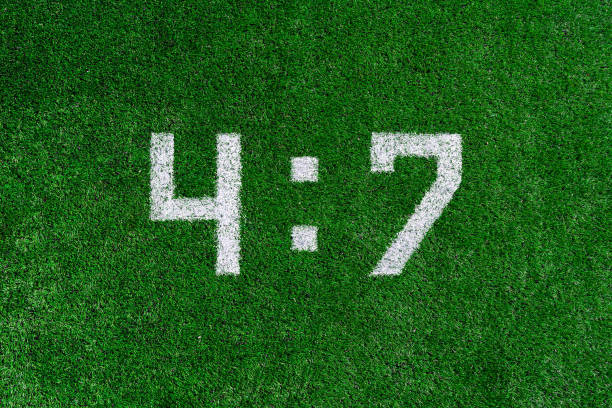 istock Football score 4:7.White numbers four and seven are drawn on the green grass,creative scoreboard 1159542968
