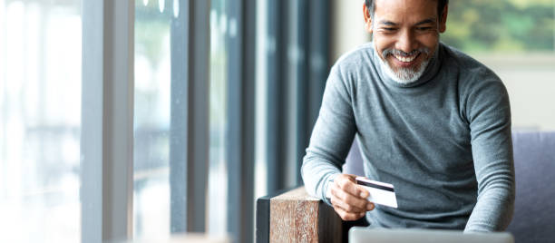 istock Attractive bearded hipster asian father or Hispanic old man using Laptop and credit card payment shopping online with customer network connection via omni channel system. Older man with technology. 1159543764