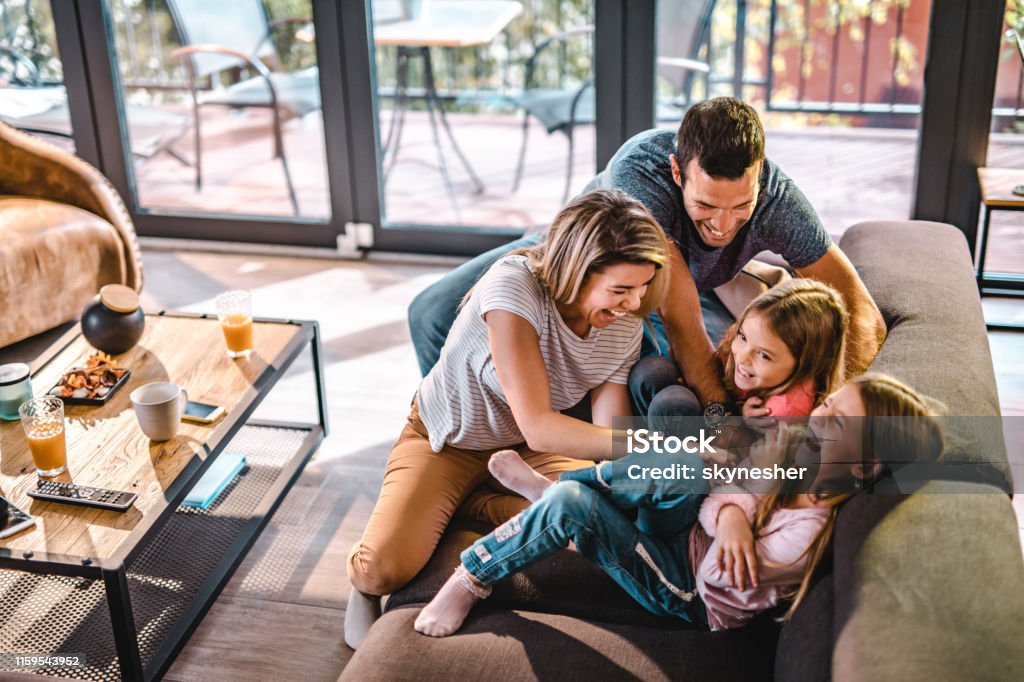 Oben der Blick auf verspielte Eltern, die ihre Töchter zu Hause kitzeln. - Lizenzfrei Familie Stock-Foto
