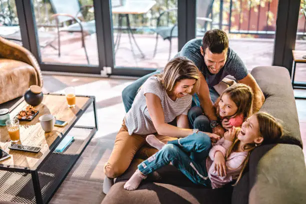 Photo of Above view of playful parents tickling their daughters at home.