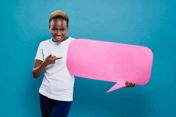 istock African girl holding speech bubble and pointing with finger. 1159544944
