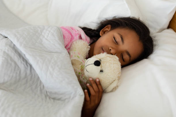istock Girl sleeping with teddy bear in bed in bedroom 1159545335