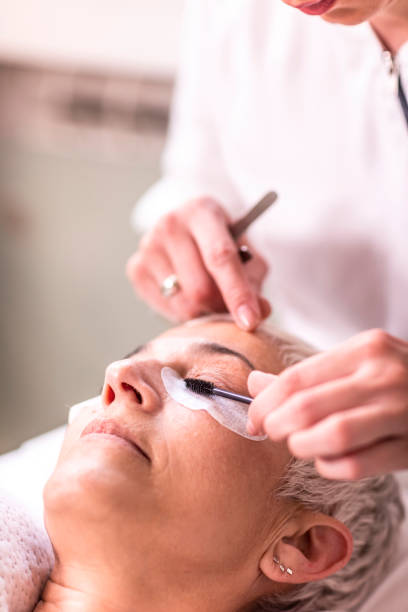 istock Elderly woman having her eyelash extensions adjusted by a professional cosmetician in a beauty parlor 1159546285