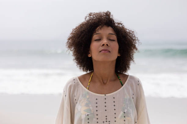 istock Woman standing with eyes closed on the beach 1159548432