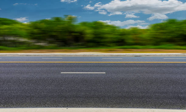 nuove strade asfaltate, alberi sotto il cielo blu e nuvole bianche - ciglio della strada foto e immagini stock