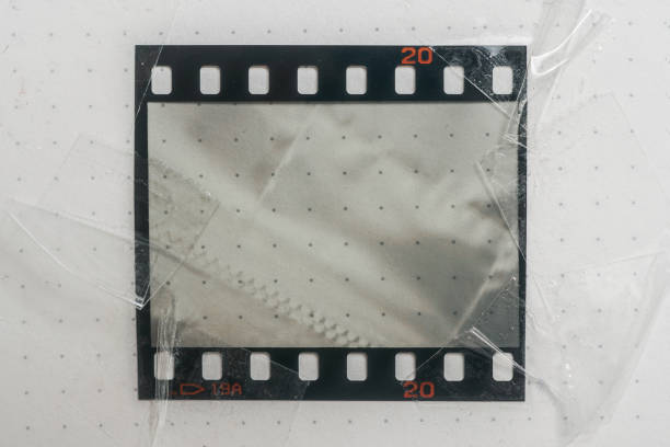 prawdziwy i oryginalny materiał filmowy 35 mm lub 135 na białym papierze, taśma filmowa 35 mm z pustym oknem lub komórką z sellotape na krawędzi - at the edge of audio zdjęcia i obrazy z banku zdjęć