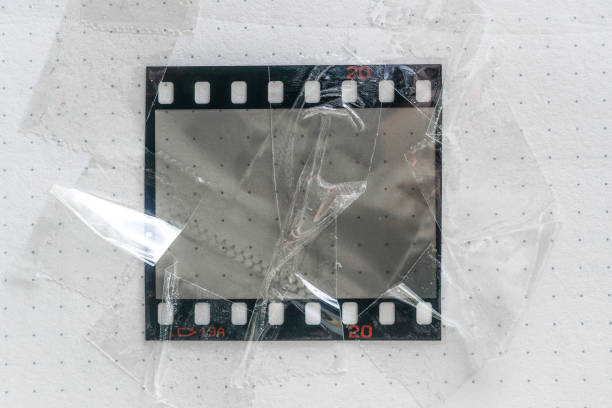matériel de film ou cadre photo réel et original de 35mm ou 135 sur fond de papier blanc, filmstrip 35mm avec fenêtre ou cellule vide avec sellotape sur le bord - at the edge of audio photos et images de collection
