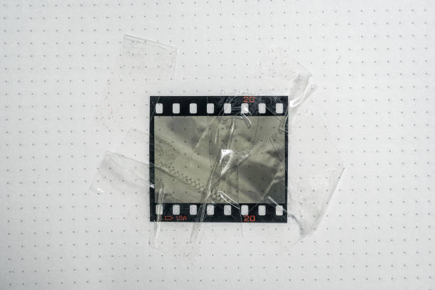 matériel de film ou cadre photo réel et original de 35mm ou 135 sur fond de papier blanc, filmstrip 35mm avec fenêtre ou cellule vide avec sellotape sur le bord - at the edge of audio photos et images de collection