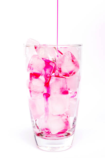 istock Pouring red syrup on ice cubes isolated on white background 1159558406