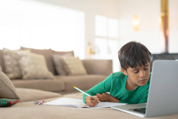 istock Boy using laptop while drawing a sketch on book at home 1159559378