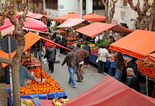 Open-air market with colorful tents and many people shopping.