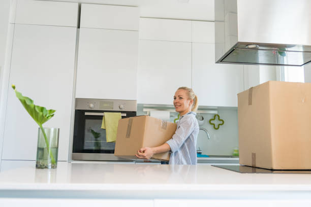 istock Young woman carrying boxes whilst moving home 1159560973