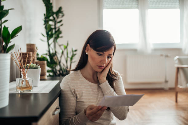 istock Stressed woman reading a letter at home. 1159562013