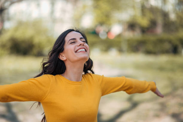 Freedom concept. Young woman spreading hands with joy, in the park.