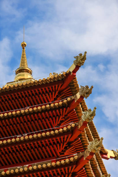 o canto do telhado multi-level vermelho do pagoda, decorado com ouro, de encontro ao céu azul com nuvens brancas claras. - corner temple stupa tower - fotografias e filmes do acervo