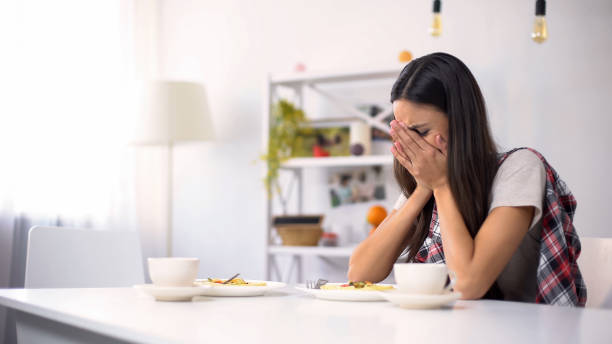istock Young sad woman sitting alone in kitchen and crying after quarrel, depression 1159562652