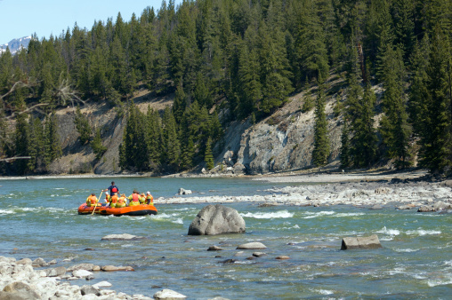Group of people on a raft coming out of whitewater section of river and celebrating.