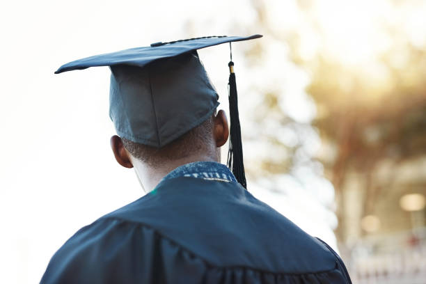 I look forward to the future Rearview shot of a young man on graduation day post secondary education photos stock pictures, royalty-free photos & images