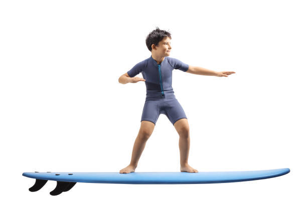 istock Boy in a wetsuit standing on a surfing board 1159567292