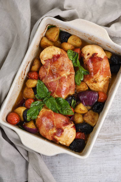 istock Chicken breast stuffed with goat cheese with spinach, wrapped in prosciutto, with slices of baked potatoes, tomatoes, and dried prunes. 1159567631