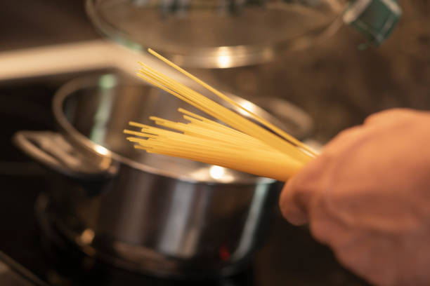 istock Man wearing a apron in the kitchen preparing food, cooking spaghetti. 1159568230