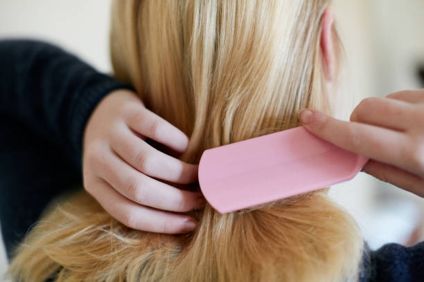 Rearview of young blonde woman brushing hair Seen from behind a young blonde woman looks into the mirror as she brushes her hair. brushing hair stock pictures, royalty-free photos & images