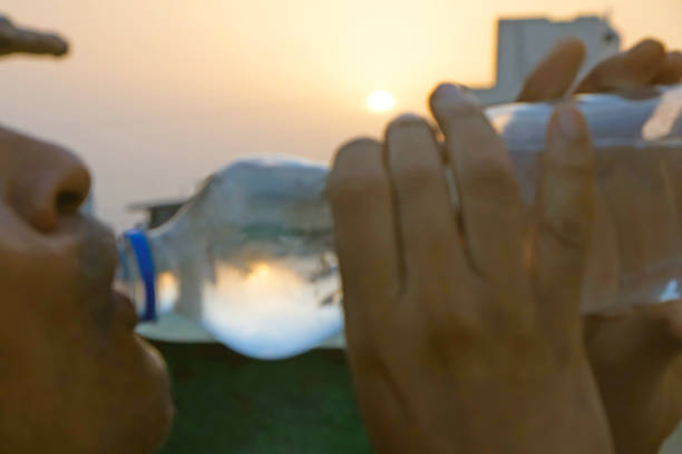 man drinking water from bottle in hot summer day outside