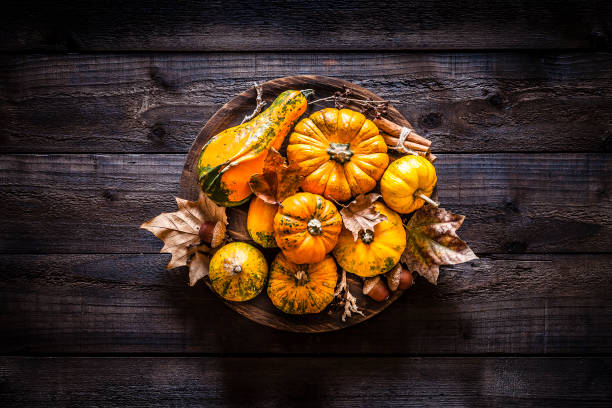 Autumnal colorful pumpkins and fallen leaves shot from above on rustic wooden table