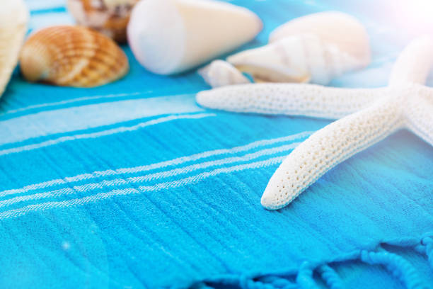 Summer Accessories Background. View of Summer Beach Accessories. Beach Hat, Sea Shells and Star Fish on a Turquoise Blue Beach Towel. Tropical Summer Concept, Nautical Life Concept. Beach Background, Vacation and Travel Concept. accesorios de verano fondo. vista de los accesorios de summer beach. sombrero de playa, conchas de mar y pescado estrella en una toalla de playa azul turquesa. concepto verano tropical, concepto de vida náutica. concepto de fondo de playa, vacaciones y vi