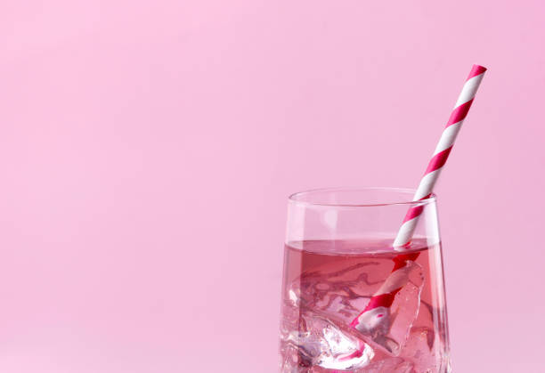 Summer refreshment drinks. Light pink rose cocktail on a pink background with striped pink straw.