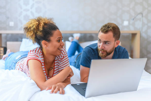 istock Young Husband and Wife Lying on Bed and Discussing Finances 1159573859