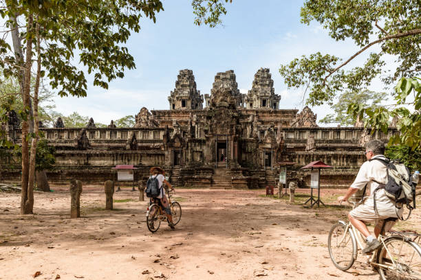 tourist couple cycling around angkor temple, cambodia. ta keo building ruins in the jungle. eco friendly tourism traveling, toned image. - angkor wat cambodia ancient angkor imagens e fotografias de stock