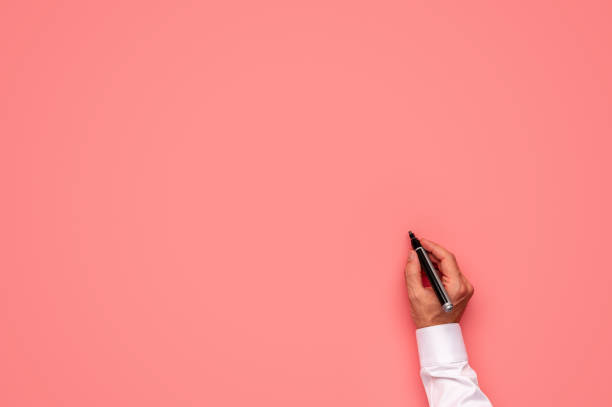 istock Male hand about to write on a blank pink background 1159577111