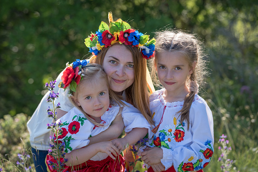 Mother and daughters in traditional Ukrainian costumes posing in the spring countryside