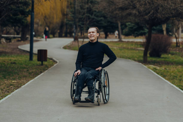 istock young disabled man in wheelchair walking park 1159580143