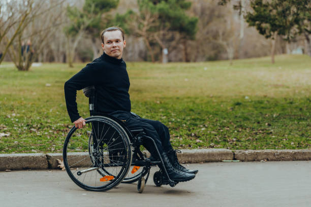 istock young disabled man in wheelchair walking park 1159580461