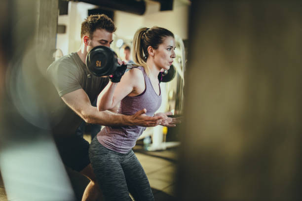 istock Athletic woman having weight training with her coach in a gym. 1159584383