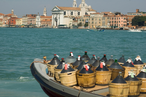 A boat delivering large wine bottles to retailers in Venice