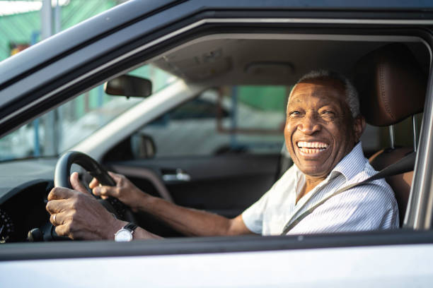 istock Smiling senior afro man driving a car and looking at camera 1159586745