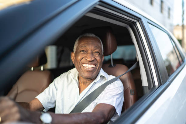 istock Smiling senior man driving a car and looking at camera 1159586746