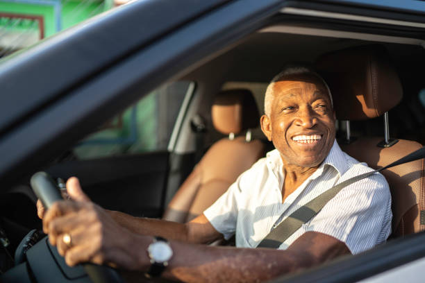 lächelnder senior, der autofährt und wegschaut - taxifahrer stock-fotos und bilder
