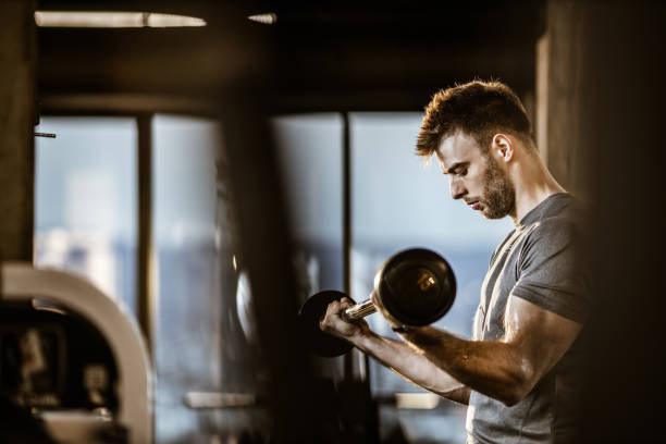 istock Muscular build man exercising with barbell in a gym. 1159586786