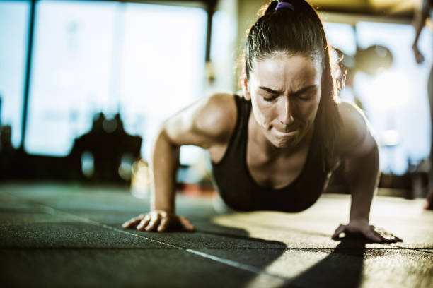 istock Athletic woman making an effort while exercising push-ups in a gym. 1159587006